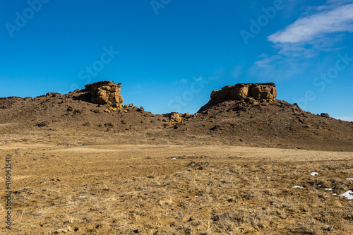 Two large rock formations in high desert field in rural New Mexico on clear day