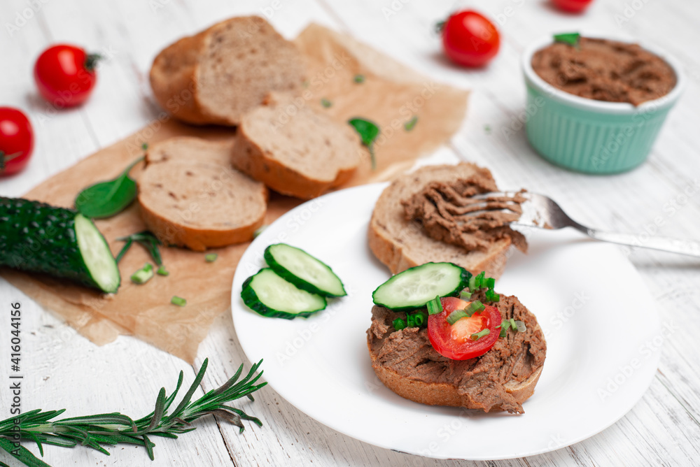Sandwiches, canapes with chicken pate, tomatoes and cucumbers. On a white wooden background. Sandwiches, canapes with chicken pate, tomatoes and cucumbers. On a white wooden background.