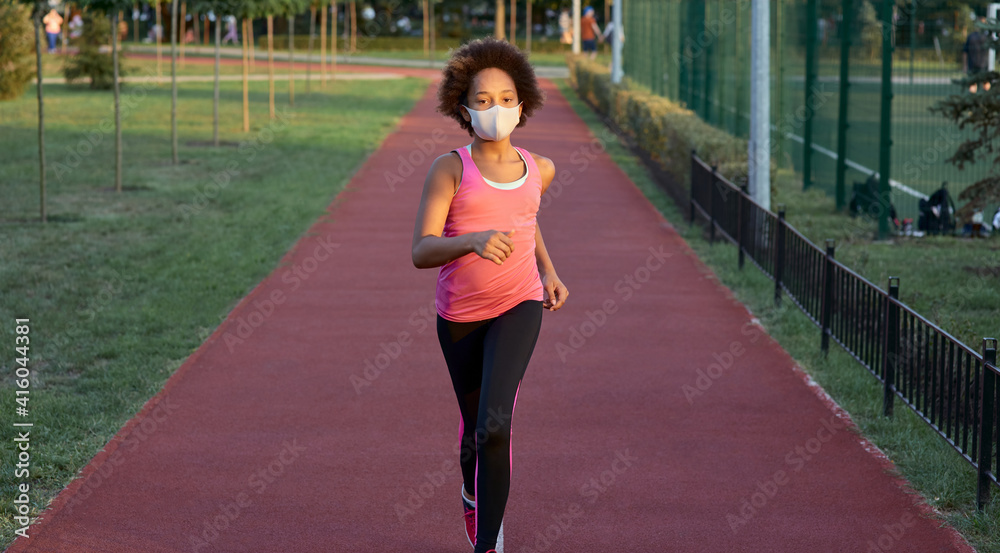 Sporty little girl in face mask running in park