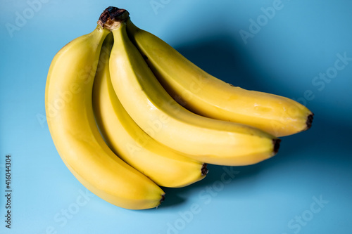 A bunch of bananas on a blue background. Vegetarian food.