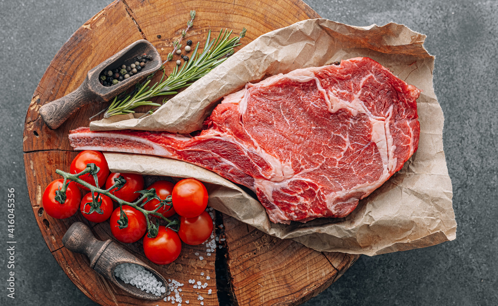 fresh raw cowboy tomahawk steak on a round wooden cutting board for meat