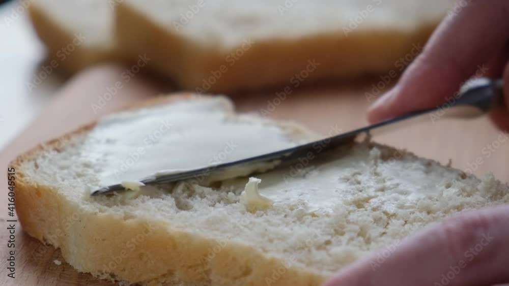 Hand smears vegan butter on yeast-free bread, close-up Hand smears vegan butter on yeast-free bread, close-up