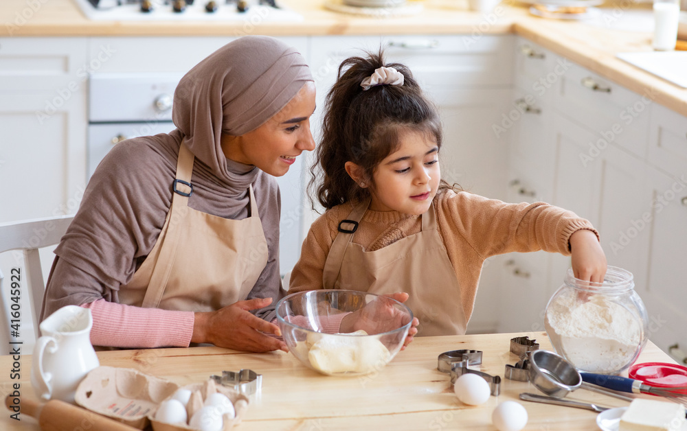 Cute Little Girl And Muslim Mom In Hijab Preparing Pastry In Kitchen Cute Little Girl And Muslim Mom In Hijab Preparing Pastry In Kitchen