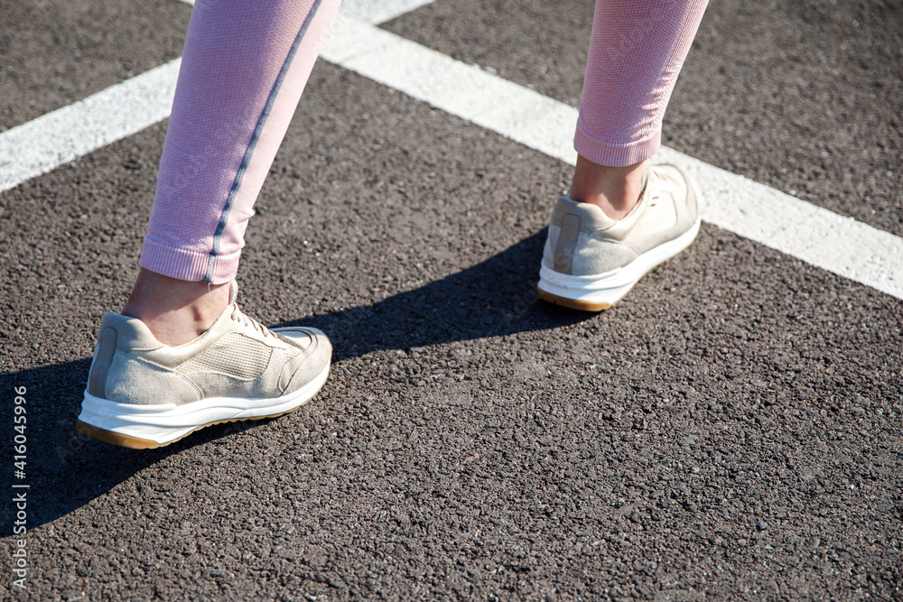 Runner legs running on the road close-up on shoes. Fitness woman jogging workout wellness concept.