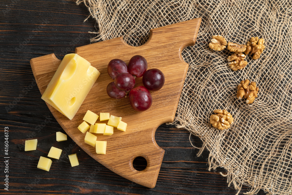 Cheese, grapes and nuts on a cutting board