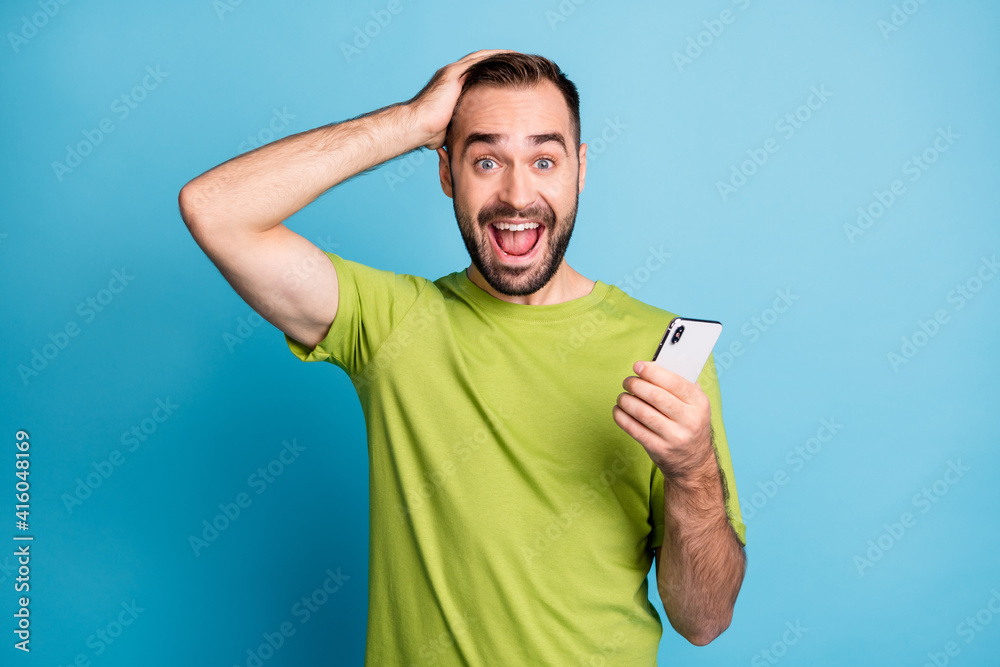 Photo of shocked brown haired guy hold phone notification sale hold hand head isolated on blue color background Photo of shocked brown haired guy hold phone notification sale hold hand head isolated on blue color background