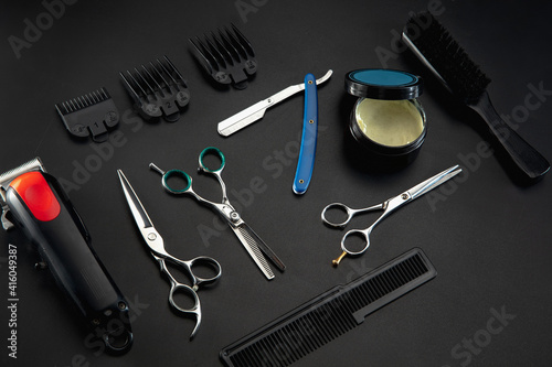 Barber shop equipment set isolated on black table background. Close up sccissors, comb, brushes, razors, professional tools of hairdresser. Professional occupation, art, self-care concept. Magazine.