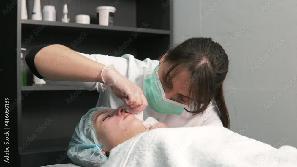Cosmetologist a woman cleans her face from black spots on her nose with her fingers. The mechanical method. Professional skin care products. Beauty salon. Cosmetologist a woman cleans her face from black spots on her nose with her fingers. The mechanical method. Professional skin care products. Beauty salon.