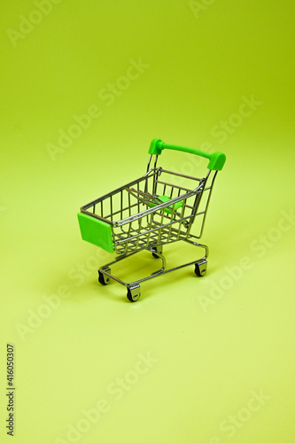 Metal mini shopping trolley isolated on a pistachio-green background with copy space, shopping symbol. Sales concept