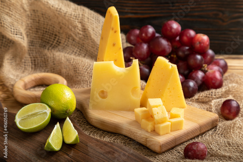 Obraz na płótnie Cheese, grapes, lime, pear and nuts on a cutting board w salonie
