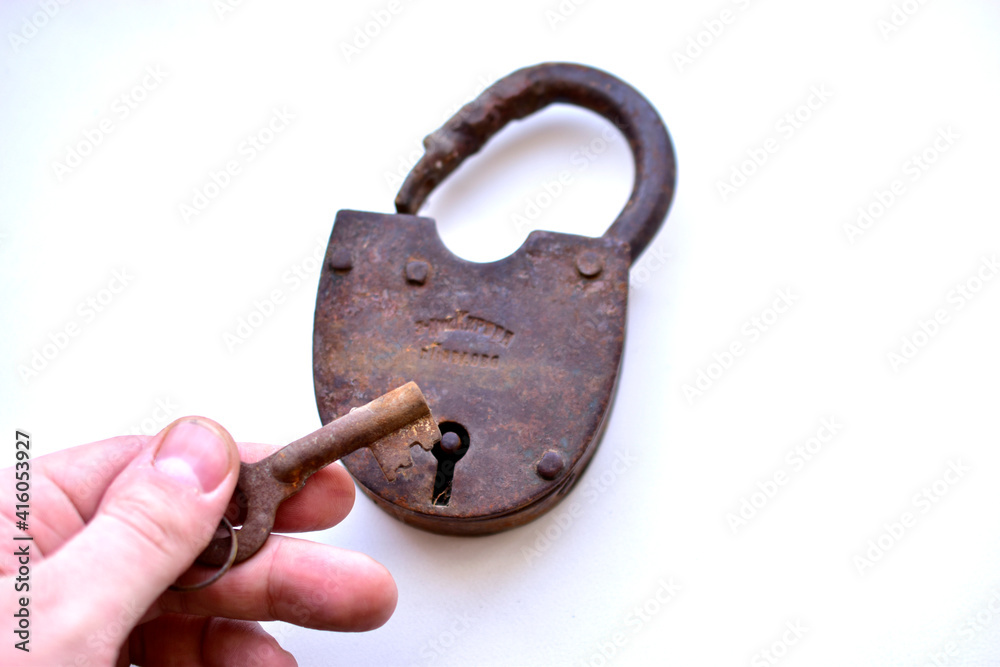 An old padlock in his hand on a white background An old padlock in his hand on a white background