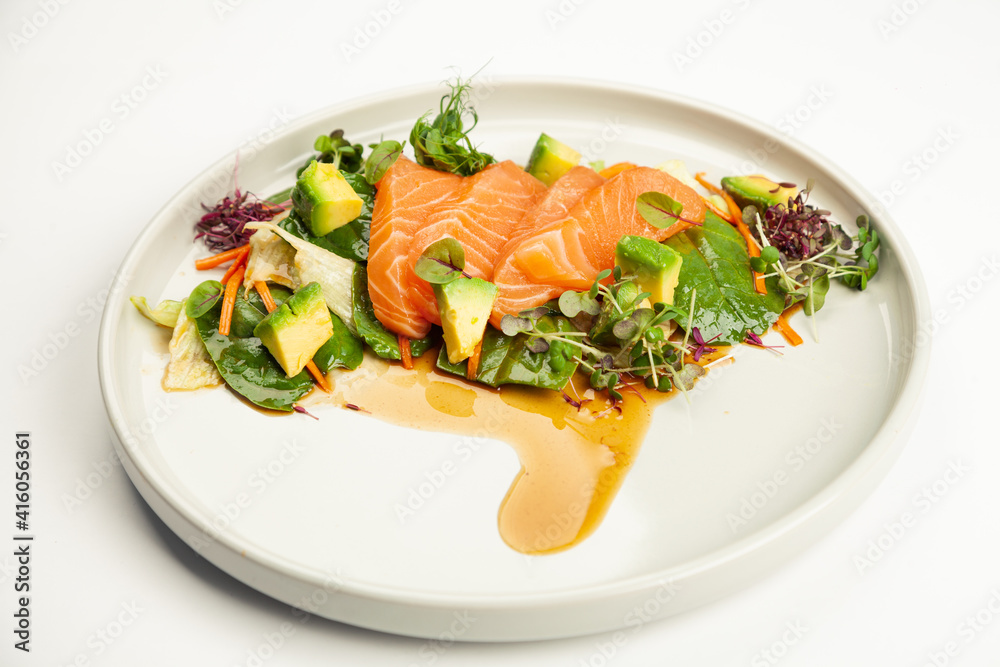 Salmon and avocado salad in tamarind sauce on a plate. Ingredients Iceberg lettuce, salmon, avocado, spinach, carrot, tamarind sauce. For restaurant menu Salmon and avocado salad in tamarind sauce on a plate. Ingredients Iceberg lettuce, salmon, avocado, spinach, carrot, tamarind sauce. For restaurant menu
