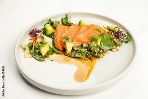 Salmon and avocado salad in tamarind sauce on a plate. Ingredients Iceberg lettuce, salmon, avocado, spinach, carrot, tamarind sauce. For restaurant menu