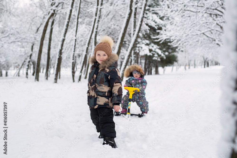 Naklejka premium Small boy pulls his little sister on a sled.