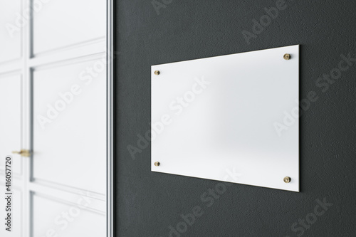 Light blank signage on dark wall before the entrance a room with white door. Mockup photo