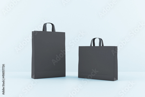 Blank black paper bags with a space for your sign at blue background. Mockup