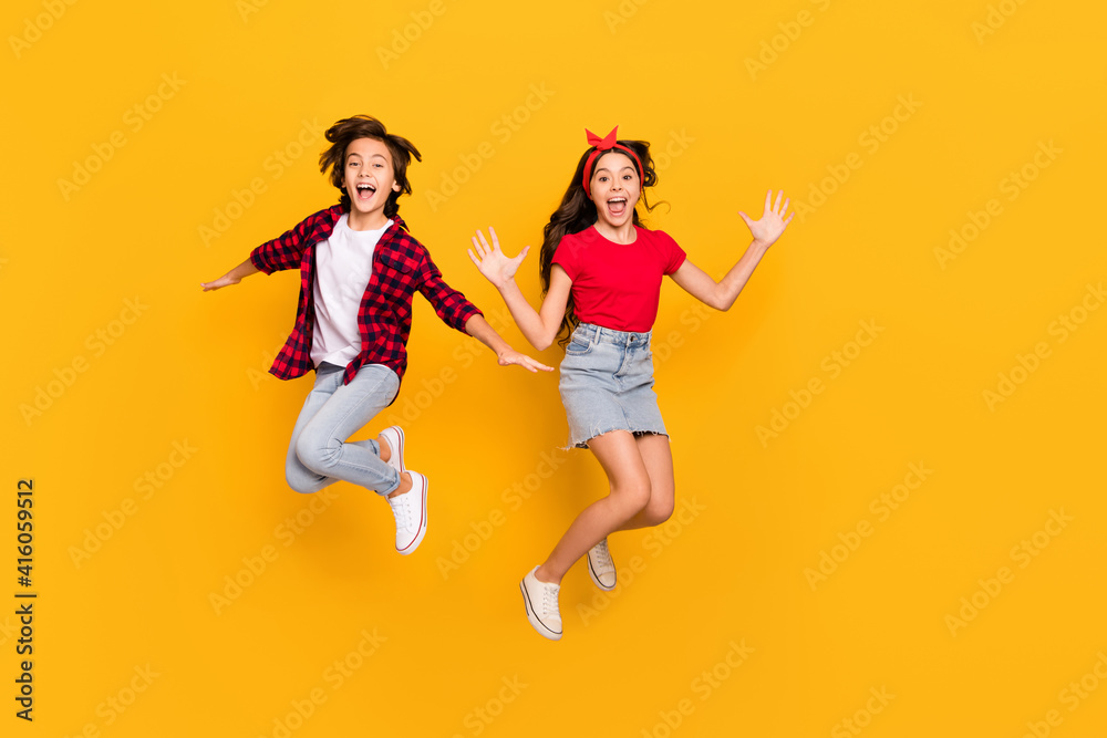 Full size portrait of two excited persons enjoy jumping open mouth isolated on yellow color background Full size portrait of two excited persons enjoy jumping open mouth isolated on yellow color background