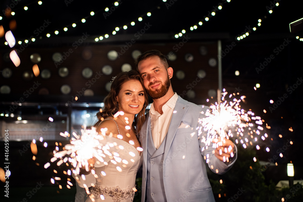 newlyweds with sparklers in night park with garlands in trees. ending to wedding newlyweds with sparklers in night park with garlands in trees. ending to wedding
