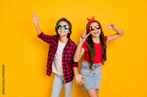 Photo of positive boy hands palms girl fingers show v-sign have good mood isolated on yellow color background