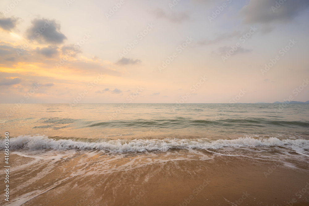 Yellow light sky and white waves on the beach in the morning, Thailand.