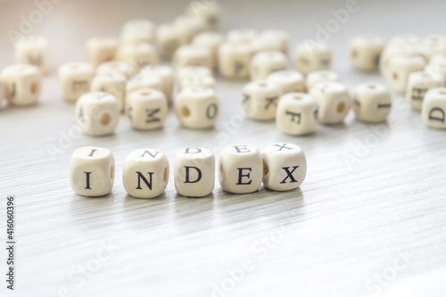 Word Index made with block wooden letters cubes in centre surrounded by pile of other letters on wooden surface. SEO concept photo