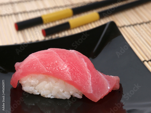 Sushi with tuna on black plate on a bamboo mat close-up