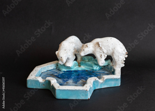 Art deco ceramic statue with polar bears and ice pool isolated on black background