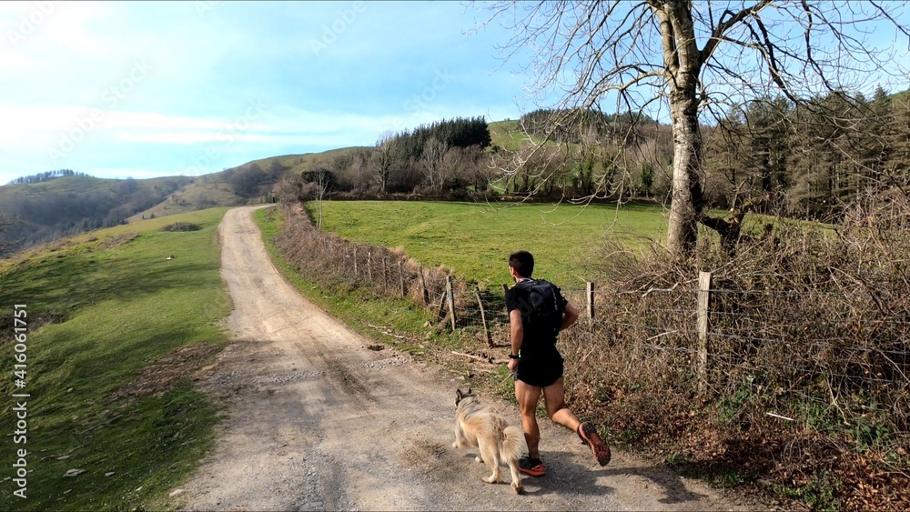 young man trail running in the mointains with his dog