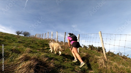 young woman trail running in the mountains with her dog