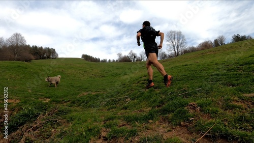 фотографія young man trail running in the mointains with his dog