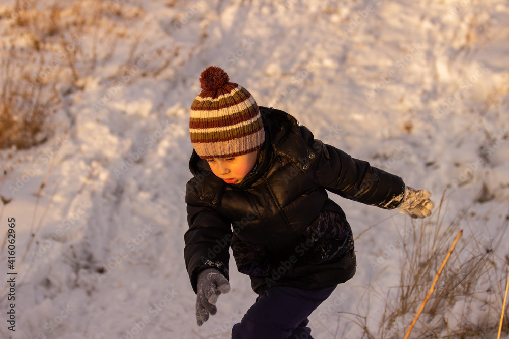 Little boy playing on a snow slide. The concept of active recreation of children in nature. Winter walks Little boy playing on a snow slide. The concept of active recreation of children in nature. Winter walks