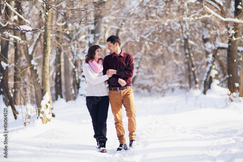 Young couple walking through the winter forest holding hands