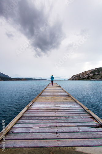 A girl stands on the pier and looks at the sea