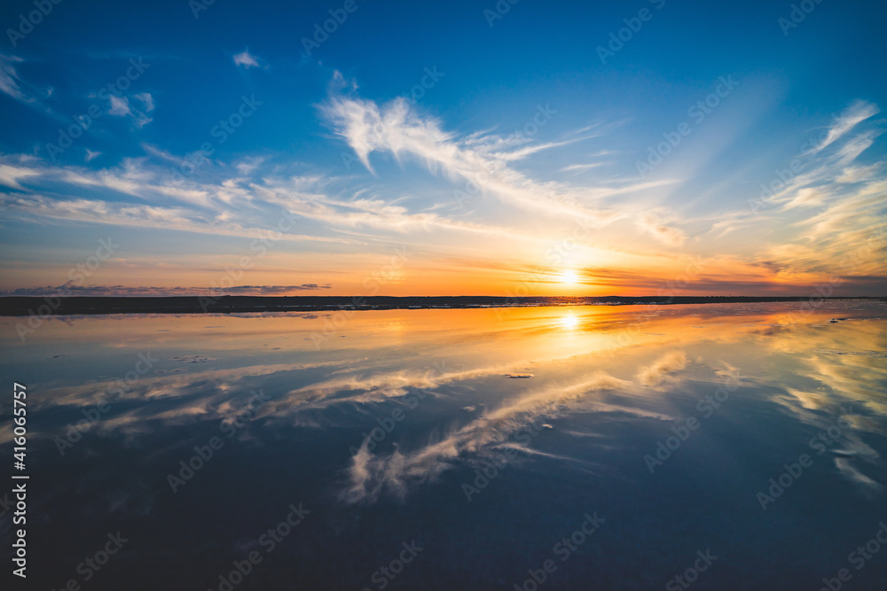 波の水たまりに反射した夕日と空と雲