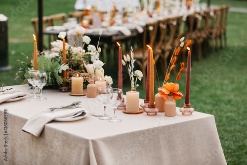 Candles, dried flowers and accessories, bouquets and glasses on table with linen tablecloth on newlywed table