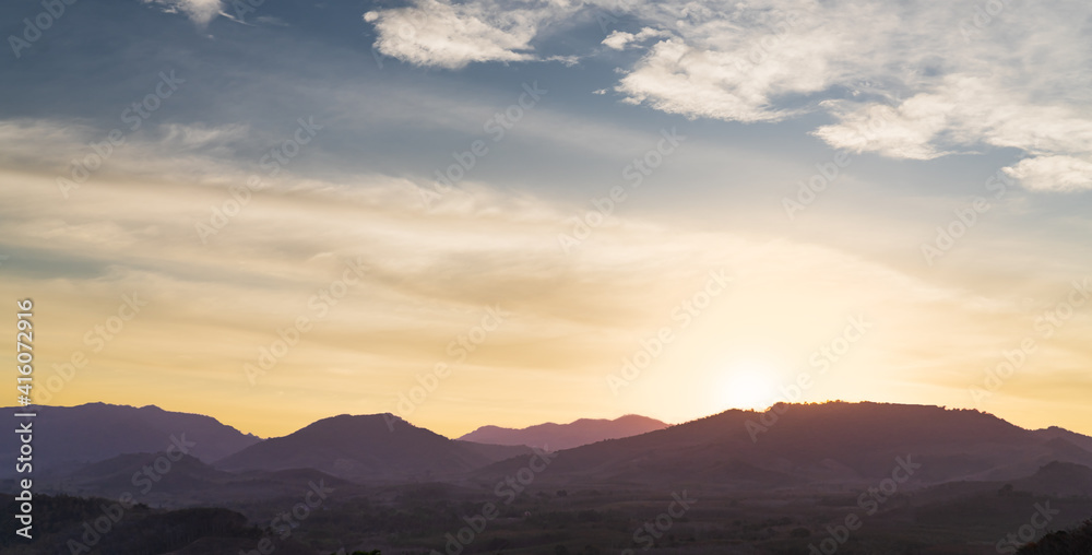 sunset over the silhouette mountains in the evening