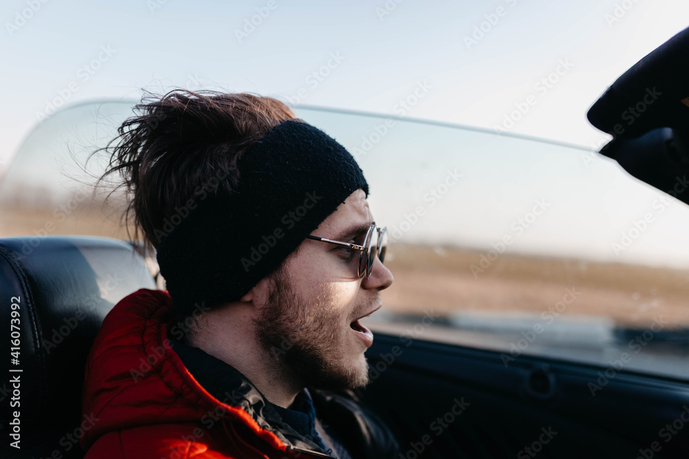 man in cold weather rides in a convertible in warm clothes. man in cold weather rides in a convertible in warm clothes.