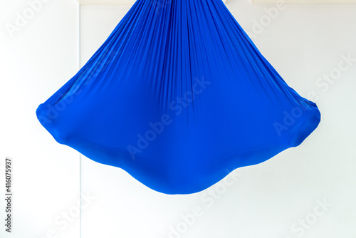 Work out on a hammock with a great yoga coach in the studio. Fly yoga. A girl lies in a blue anti gravity yoga hammock in shavasana.
