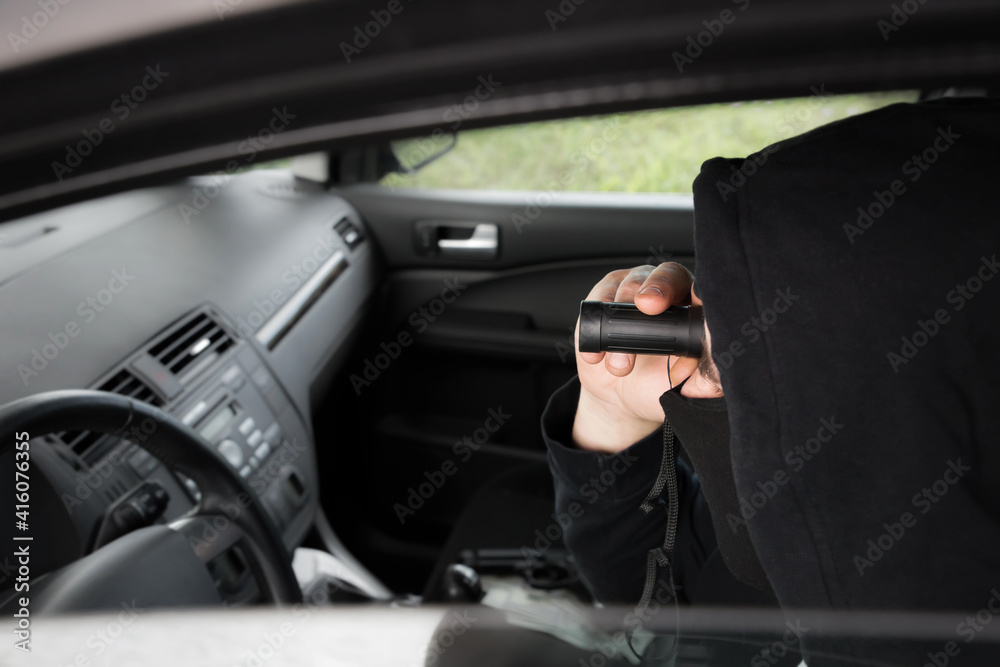 Spying from the car. Man with binoculars in black clothes. Criminal concept. Spying from the car. Man with binoculars in black clothes. Criminal concept.