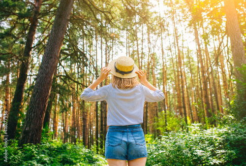 Hipster girl in straw hat standing in the forest. Wanderlust concept. Travelling ideas. Beautiful woman in the nature. Summer vibes. © Vadym