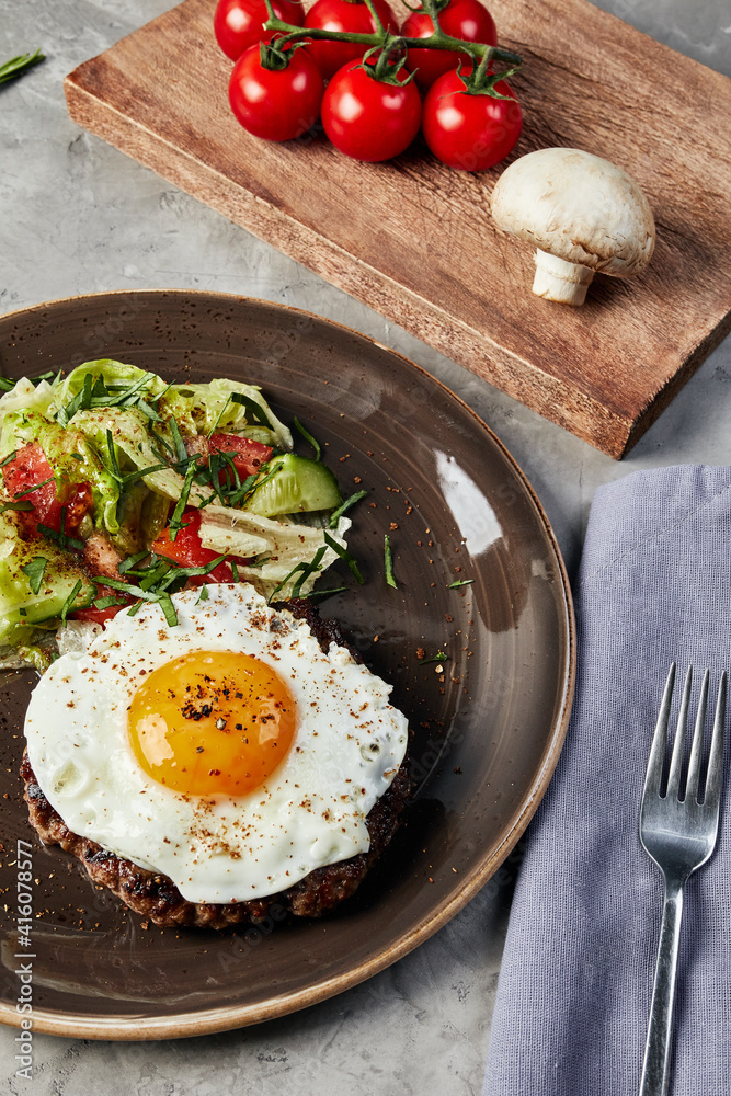 scrambled eggs and salad on a brown plate next to a wooden board with tomatoes and mushroom on a gray concrete background scrambled eggs and salad on a brown plate next to a wooden board with tomatoes and mushroom on a gray concrete background