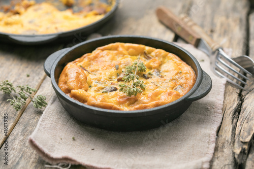 Frittata with mushrooms in a pan on wooden background. Fritata is an Italian breakfast dish.