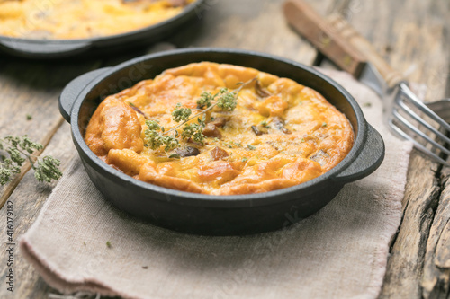 Frittata with mushrooms in a pan on wooden background. Fritata is an Italian breakfast dish.