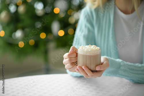 Beautiful young woman drinking hot chocolate at home on Christmas eve  closeup