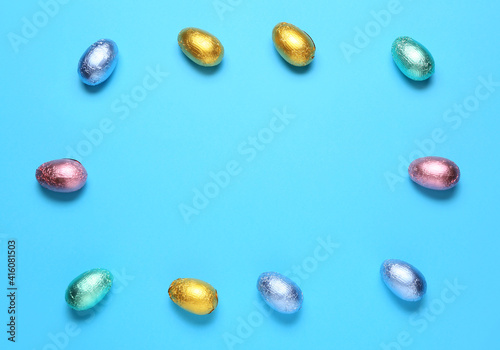 Frame made of sweet chocolate eggs on color background