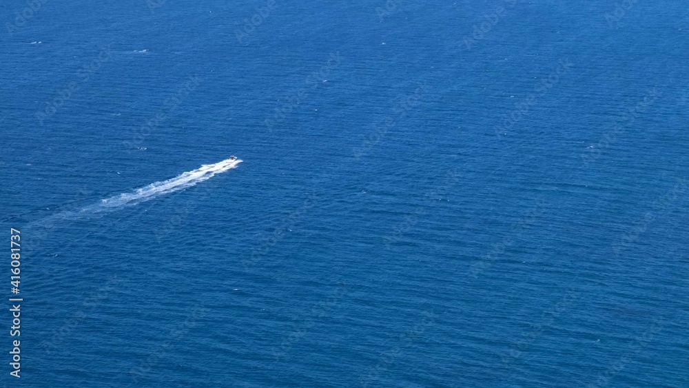 Naklejka premium small boat moves on a beautiful blue sea