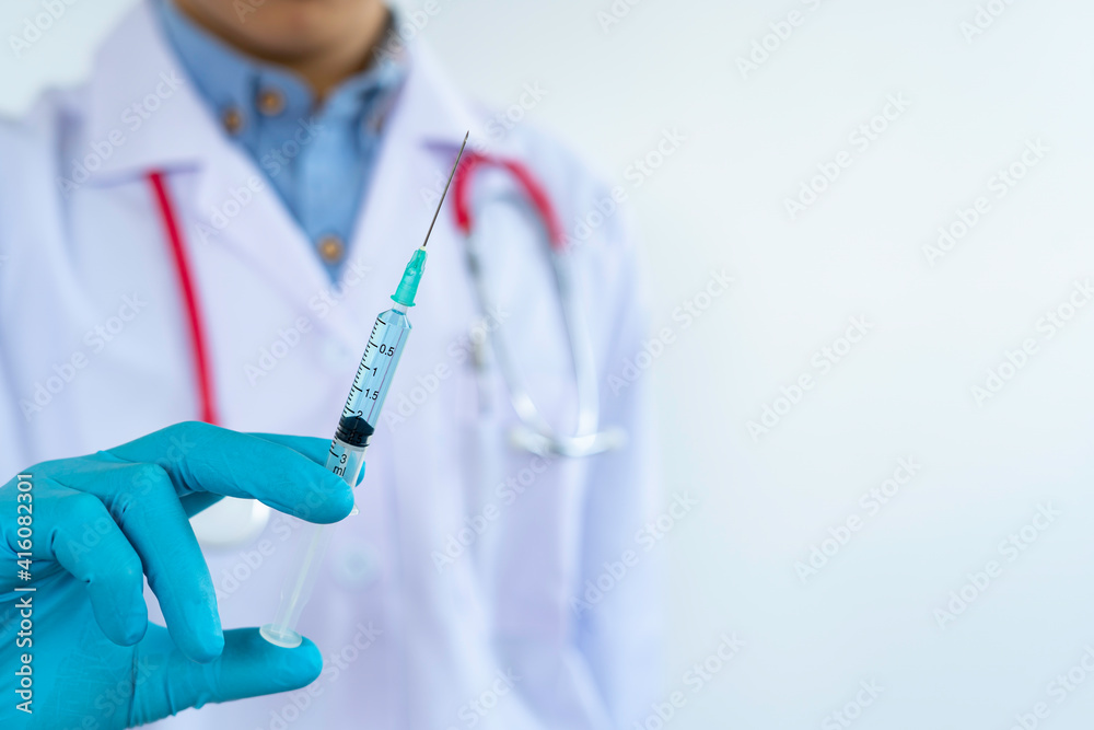 The doctor in blue gloves holds a syringe with a prepared injection from a needle. A surgeon holding a syringe With a new vaccine for the coronavirus The doctor in blue gloves holds a syringe with a prepared injection from a needle. A surgeon holding a syringe With a new vaccine for the coronavirus