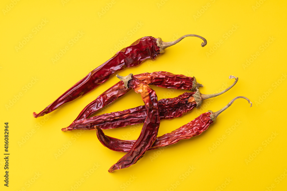 Dry red pepper pods on yellow background Dry red pepper pods on yellow background