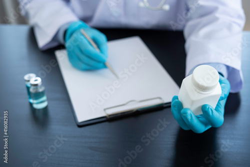 A doctor in blue gloves or a pharmacist with a bottle of medicine in hand is writing a patient treatment guide, patient dispensing and treatment ideas.