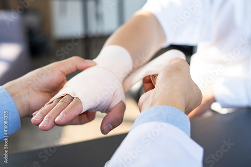 A doctor wrapped around the wrist for first aid Close-up with a particular emphasis on the application of bandages on the patient's hands, first aid concepts and wrist injury treatment.